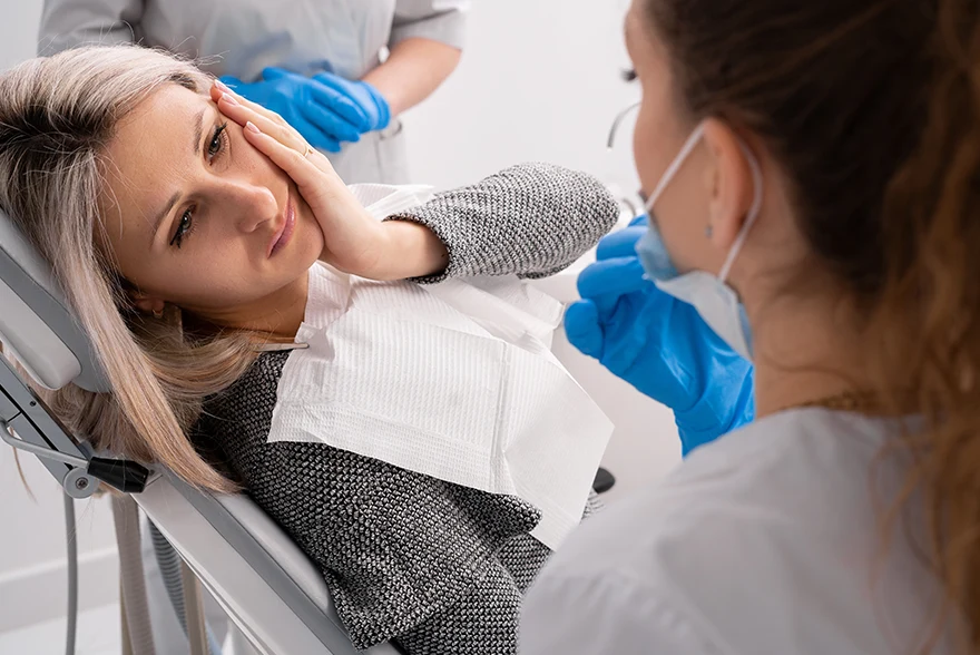 Woman holding her left cheek to show wisdom tooth pain to dentist and request for a wisdom tooth extraction in Jacksonville, FL