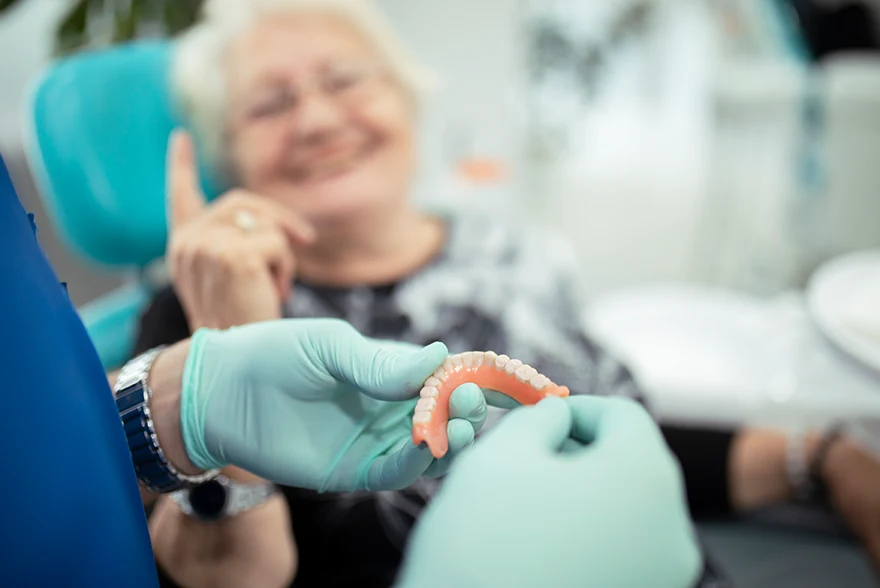 Image of a doctor explaining snap on dentures to a patient sitting in a dental chair