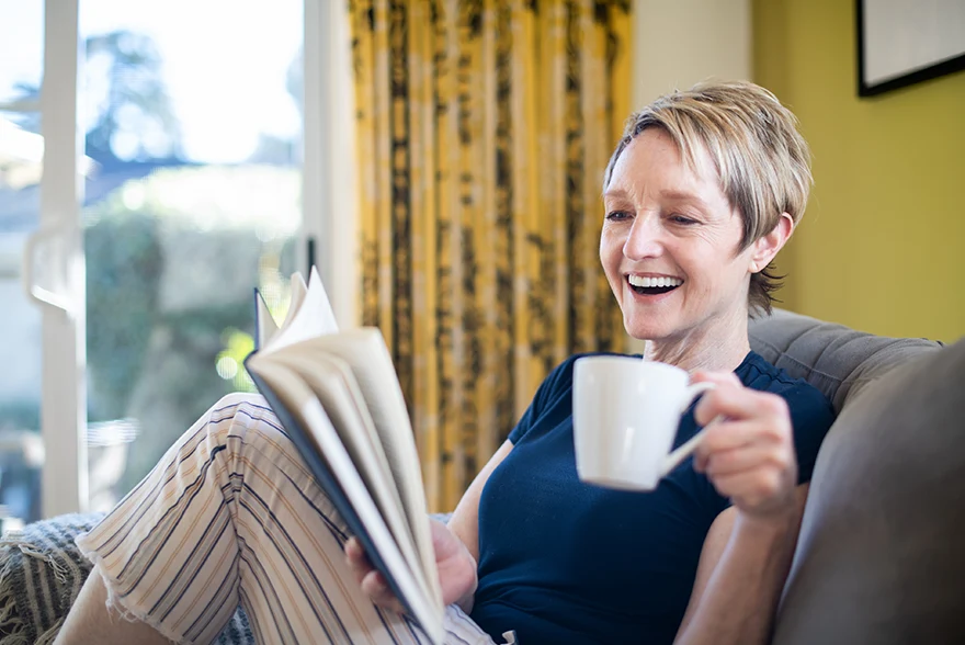 Happy person sitting on a sofa and enjoying a cup of coffee.