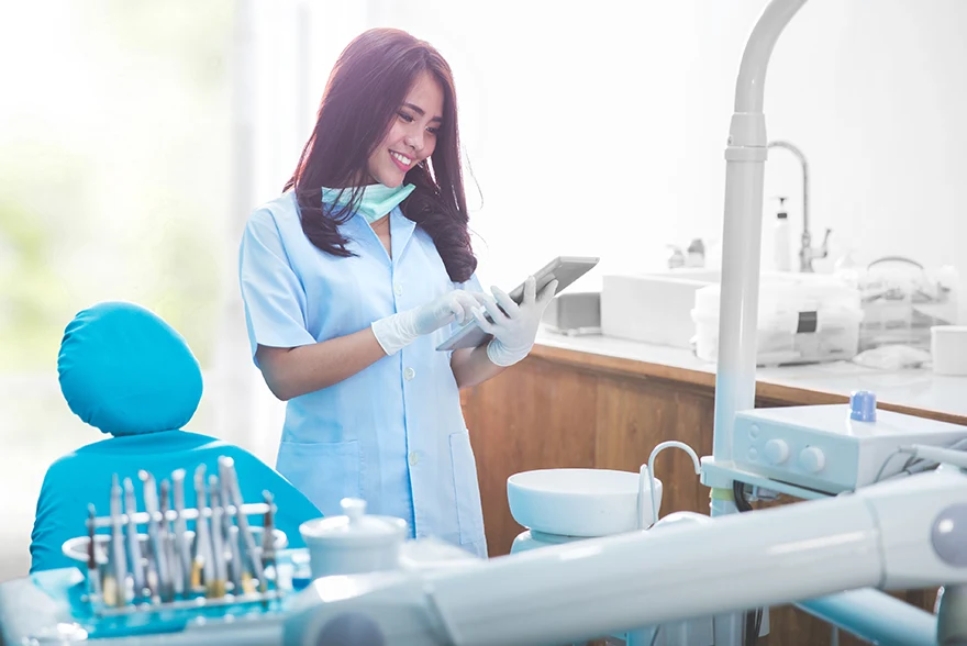 Doctor assessing the chart of a patient while standing next to a dental chair